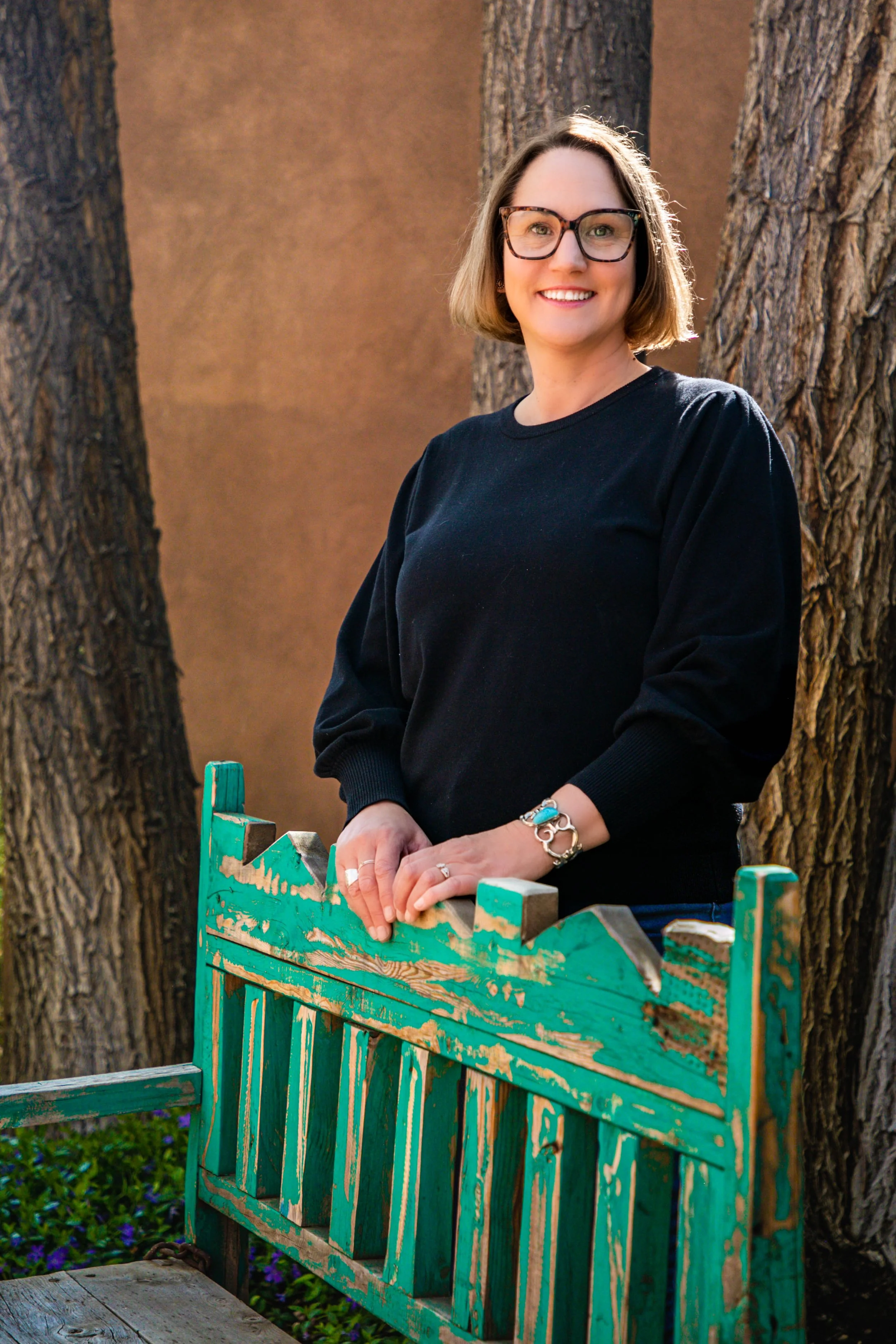 Tracey smiling beside a turquoise gate